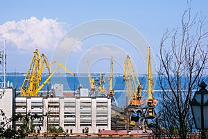 Bulk carrier ship under load of clinker cargo loading by shore cranes with grabs. Sea trading port activity. Bulk cargo