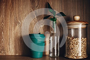 Bulk store shopping. Glass jar with cereals, reusable coffee cup and bamboo leaves on wooden shelf. Zero waste concept,