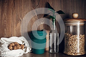 Bulk store shopping. Glass jar with cereals, textile reusable bags with nuts, reusable coffee cup and bamboo leaves on wooden