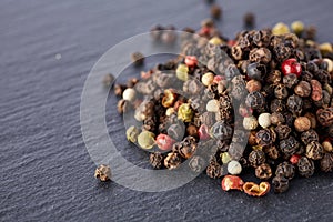 Bulk of various pepper peppercorns seeds mix on dark stone