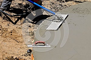 Bull float and hand trowel in usage on a concrete project