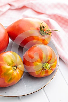 Bull heart tomatoes on plate on white table