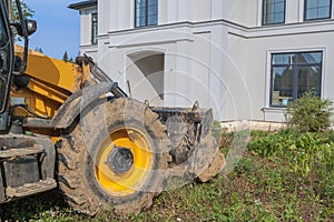bulldozer is being prepared to demolish an illegally built private house in natural area. Close - up photo of tractor bucket in