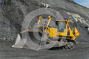 A bulldozer cleans a gold mine site in an open pit.