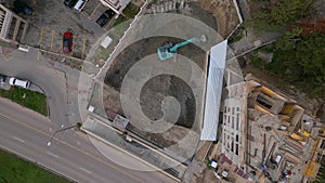 A bulldozer is digging a pit for the construction of another building in the middle of the city, aerial view