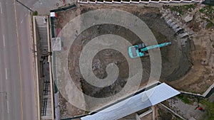 A bulldozer is digging a pit for the construction of another building in the middle of the city, aerial view