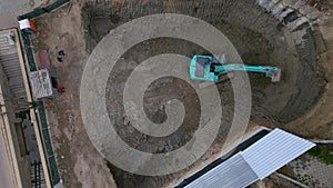 A bulldozer is digging a pit for the construction of another building in the middle of the city, aerial view