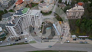 A bulldozer is digging a pit for the construction of another building in the middle of the city, aerial view