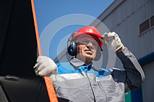 Bulldozer driver coal mine in uniform with helmet and headphones looking to side. Concept man industrial portrait