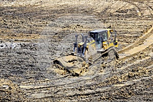 Bulldozer in excavation pit leveling the ground