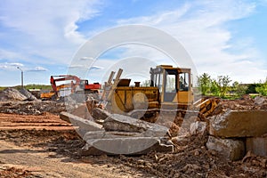 Bulldozer and excavator at landfill for work concrete demolition waste. Salvaging and recycling, reuse of building rubble. Dozer