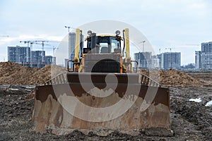 Bulldozer during land clearing and foundation digging at large construction site.  Crawler tractor with bucket for pool excavation