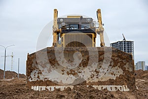 Bulldozer during land clearing and foundation digging at large construction site.  Crawler tractor with bucket for pool excavation