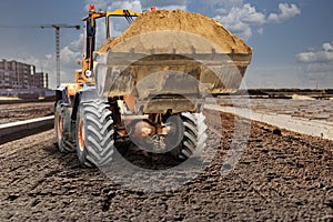 Bulldozer or loader moving sand on a construction site during the construction of a new road. An earthmoving machine is leveling