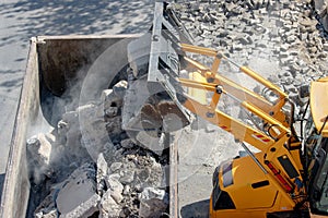 Bulldozer loader uploading concrete debris into dump truck