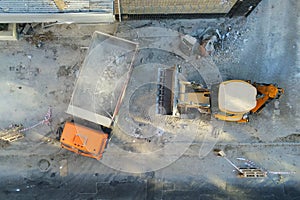 Bulldozer loader uploading waste and debris into dump truck at construction site. building dismantling and construction