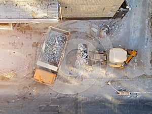 Bulldozer loader uploading waste and debris into dump truck at construction site. building dismantling and construction