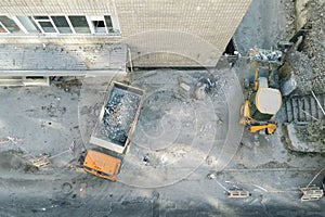 Bulldozer loader uploading waste and debris into dump truck at construction site. building dismantling and construction