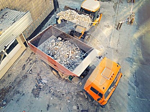 Bulldozer loader uploading waste and debris into dump truck at construction site. building dismantling and construction