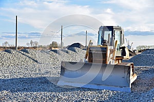 Bulldozer moves gravel during on road work at construction site. Dozer leveling stones for laying asphalt on a new freeway. Heavy