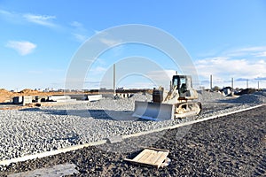 Bulldozer moves gravel during on road work at construction site. Dozer leveling stones for laying asphalt on a new freeway. Heavy