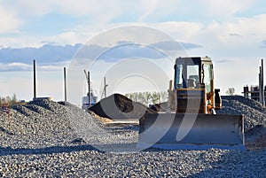 Bulldozer moves gravel during on road work at construction site. Dozer leveling stones for laying asphalt on a new freeway. Heavy