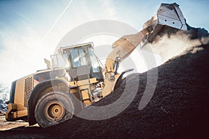 Bulldozer putting biomass on pile for composting