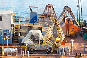 Bulldozer and rusty scoop of cargo crane on the ship deck