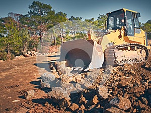 Bulldozer shovels soil at road construction works