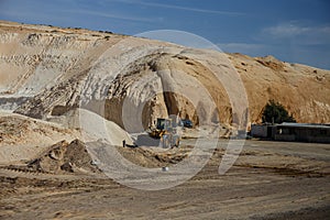 Bulldozer in the stone quarry in the middle of the day.