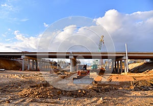 Bulldozer working at construction highway ramps and bridgeworks. Roundabout and traffic bridge construction. Road work on traffic