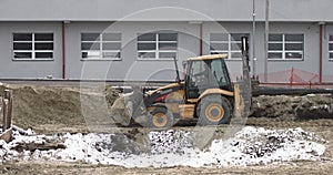 The bulldozer works on a construction site with sand, side view. New Big Tractor, a bulldozer on wheels on a sandy road