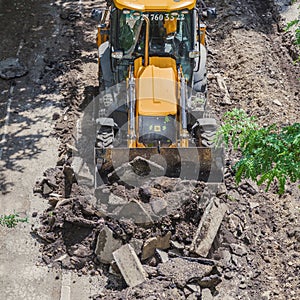 Bulldozer works on the repair of the intra-block road and sidewalk