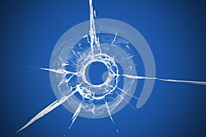 Bullet hole in glass close up on blue background