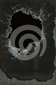 a bullet hole in glass is a real bullet hole of a large caliber projectile bullet. Glass door pierced by a bullet during the war,