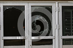 a bullet hole in glass is a real bullet hole of a large caliber projectile bullet. Glass door pierced by a bullet during the war,