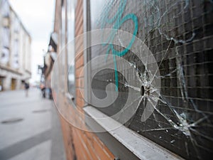 Bullet hole in a window with graffiti