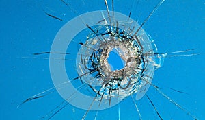 Bullet holes in the glass on the background of the blue sky.