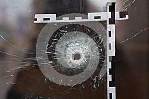 bullet holes in a glass shop window marked with a police tape