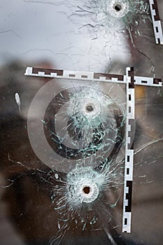 bullet holes in a glass shop window marked with a police tape