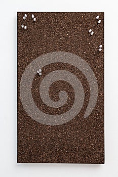 Bulletin board from dark brown cork material with transperent pins for stickers. Textured wooden cork closeup