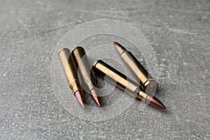 Bullets on light grey table, closeup. Firearm ammunition