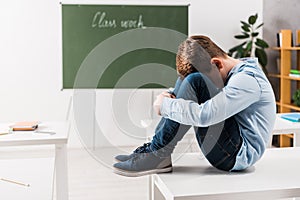 Bullied schoolchild covering face while crying