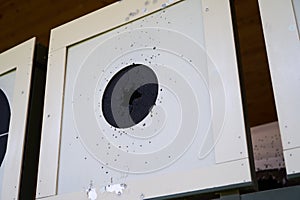 Bullseye target with bullet holes in center, close-up. Gun shooting range