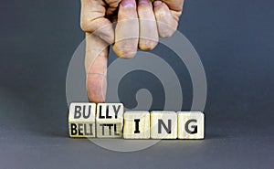 Bullying and belittling symbol. Concept words Bullying and Belittling on wooden cubes. Businessman hand. Beautiful grey table grey