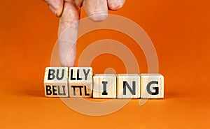 Bullying and belittling symbol. Concept words Bullying and Belittling on wooden cubes. Businessman hand. Beautiful orange table