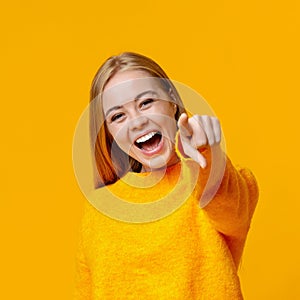 Young girl laughing at someone and pointing finger to camera photo