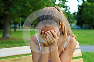 Bullying, discrimination or stress concept. Sad teenager crying alone in the park. Upset young female student having anxiety