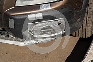 The bumper and headlight of the car are repaired with reinforced tape
