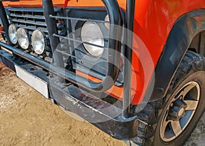 Bumper, wheel and headlights of a red SUV close up